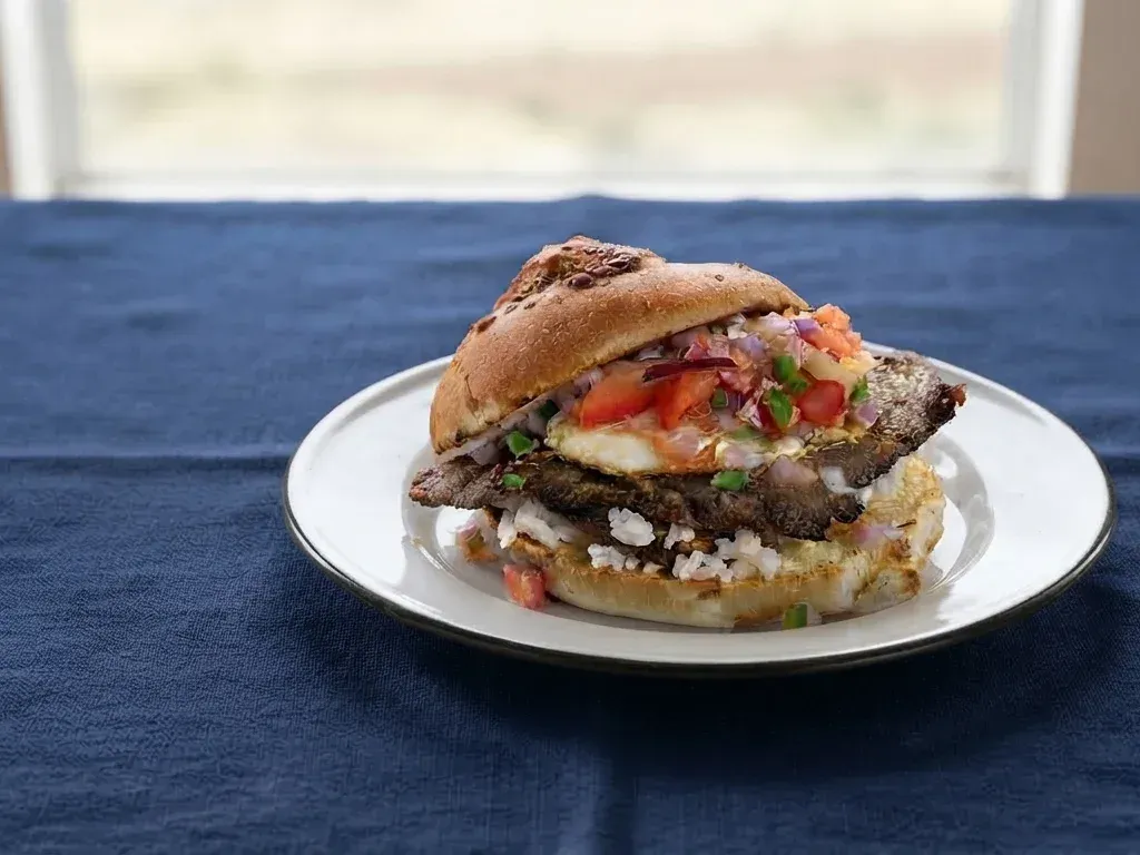 Trancapecho cochabambino, el tradicional sándwich boliviano con silpancho de carne, arroz, huevo frito, papas doradas y salsa k'allu.